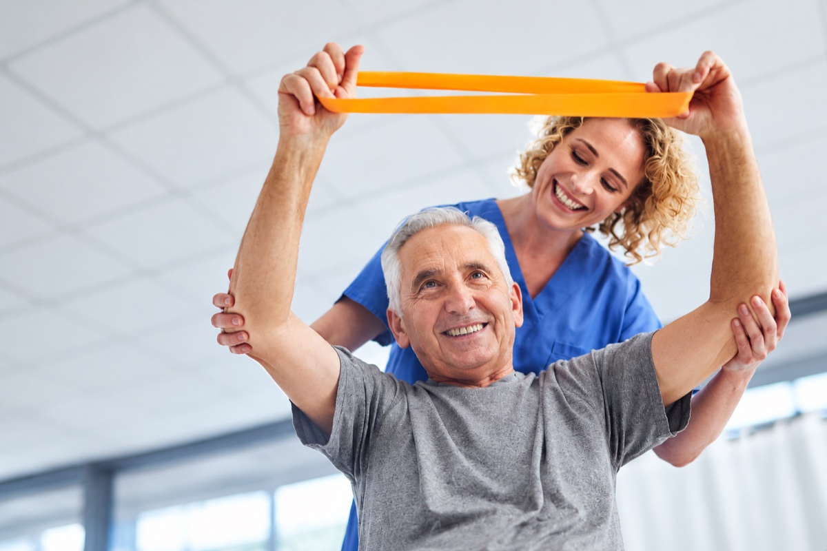 Therapist guiding orthopedic rehabilitation with a resistance band